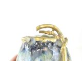 a hand holding a blue and gold purse with a gold handle