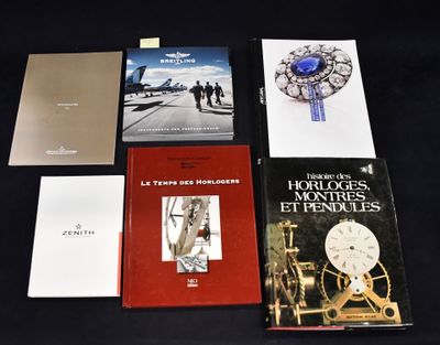 plusieurs livres posés sur une table noire, sur laquelle se trouvent une horloge et d'autres objets