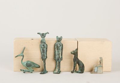 trois figurines en bronze représentant des animaux et un oiseau, posées sur un bloc de bois