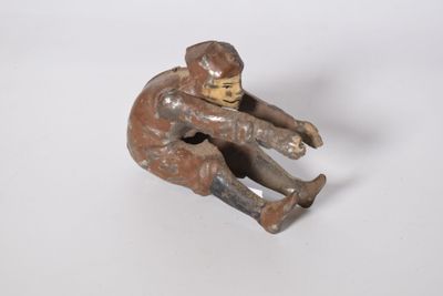 figurine of a boy sitting on a skateboard on a white surface