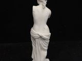 a white statue of a woman sitting on top of a black surface