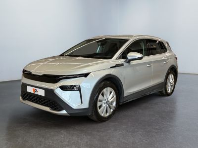 La voiture argentée est garée dans une grande pièce au sol gris.