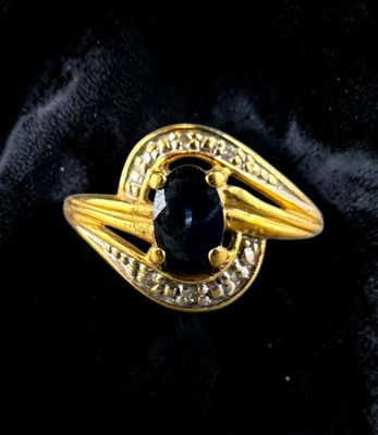 a close up of a gold ring with a black stone