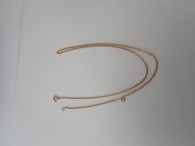 the gold chain is laying on top of a white surface
