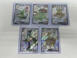 quatre cartes à collectionner Pokémon différentes, rangées dans des pochettes en plastique posées sur une surface blanche
