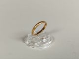 a close up of a gold wedding ring on a clear stand