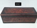 an old wooden box with a black lid on a white table
