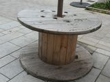 a wooden spool sitting on top of a table on a sidewalk