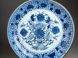 a blue and white plate with flowers on it on a stand