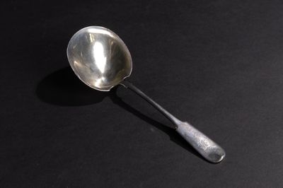 une cuillère en argent dont le manche se détache sur un fond noir