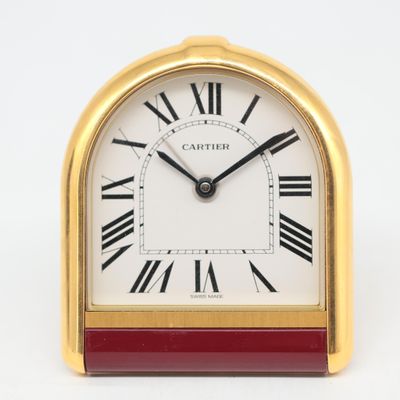 une image représentant une horloge dorée et rouge avec des chiffres romains
