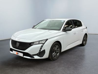 Une voiture blanche est garée dans une pièce au sol noir.