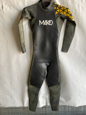 a wet suit hanging on a wall next to a surfboard