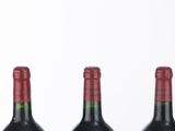 three bottles of wine are lined up in a row on a white surface