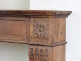 a wooden mantle with a clock on the wall behind it