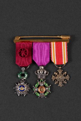 three medals are displayed on a black surface with a gold pin
