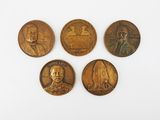 four bronze coins with portraits of people on them on a white surface