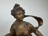 a bronze statue of a woman holding a bird in her hand