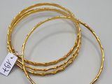 a set of three gold bang bracelets with a tag