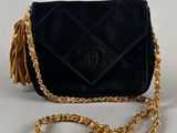 a black purse with a gold chain strap and tassel