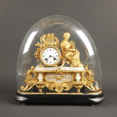 une horloge en or sous un dôme de verre sur une table