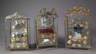 Trois horloges anciennes sont exposées sur une table recouverte d'un tissu rouge