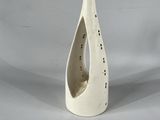 un vase blanc percé d'un trou, sur fond blanc