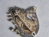 an image of a silver brooch with a sword on it