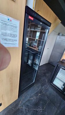 a person that is pointing at a refrigerator in a kitchen