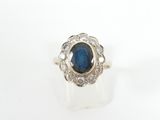 a close up of a ring with a blue stone surrounded by diamonds
