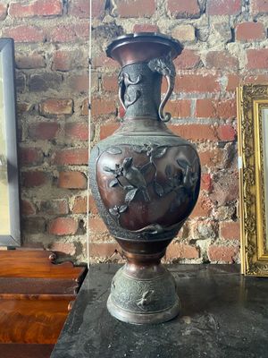 un vase posé sur une table à côté d'un tableau