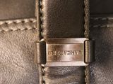 the handle of a brown leather bag with a metal buckle