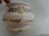 a hand that is holding a small vase on a shelf