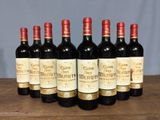 six bottles of red wine are lined up on a wooden table
