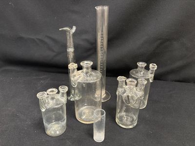 four clear glass beaks and a glass pipe with a black background