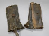 pair of old leather boots on a white surface with a leather strap