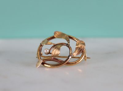 gold plated ring with leaves and pearls on a marble surface