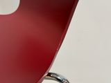 un gros plan d'une chaise rouge avec une pomme blanche posée sur le dossier