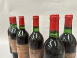 six bottles of wine are lined up in a row on a white surface