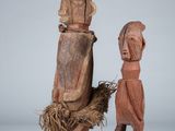 two wooden sculptures of a man and a woman standing next to each other