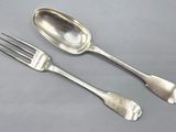 two silver spoons and a fork on a table