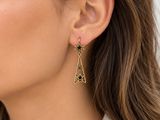 une femme vêtue d'une chemise blanche et portant des boucles d'oreilles en or