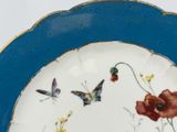 a blue plate with a butterfly and flowers painted on it