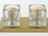 two small glass candles on a wooden stand