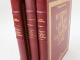 trois livres rouges sont empilés sur une surface blanche