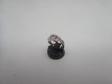 un gros plan d'une bague en diamant rose posée sur un socle noir
