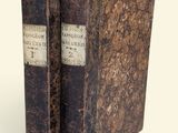 un vieux livre posé sur une table à côté d'un mur blanc