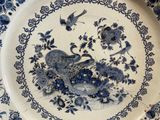 a blue and white plate with a bird and flowers on it