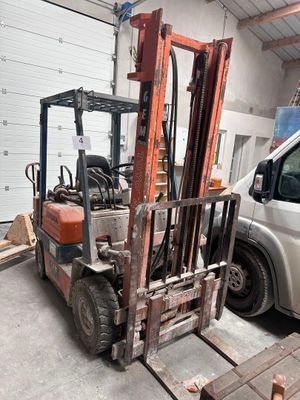un chariot élévateur garé dans un garage à côté d'une camionnette blanche