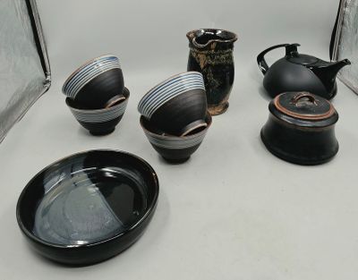 several black and white dishes and cups on a white table